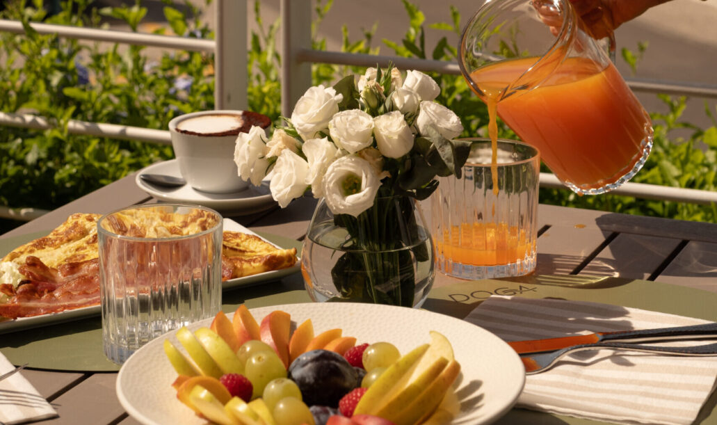 Una tavola imbandita per la colazione su una terrazza vista mare al Marina di Scarlino, con caffè, frutta fresca e yacht ormeggiati sullo sfondo.